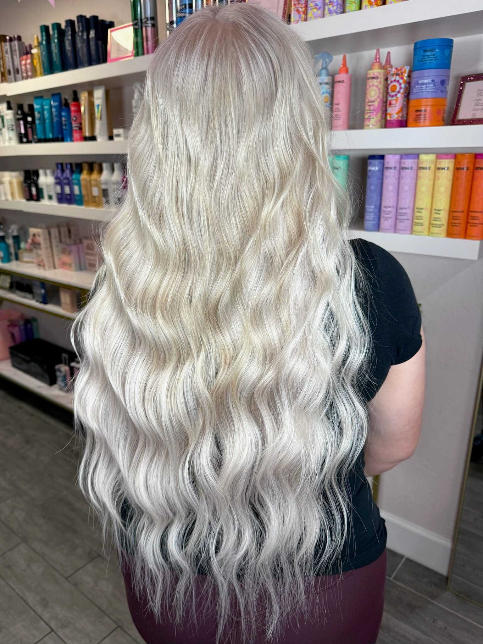 Long, wavy platinum blonde hair viewed from the back in a salon setting.