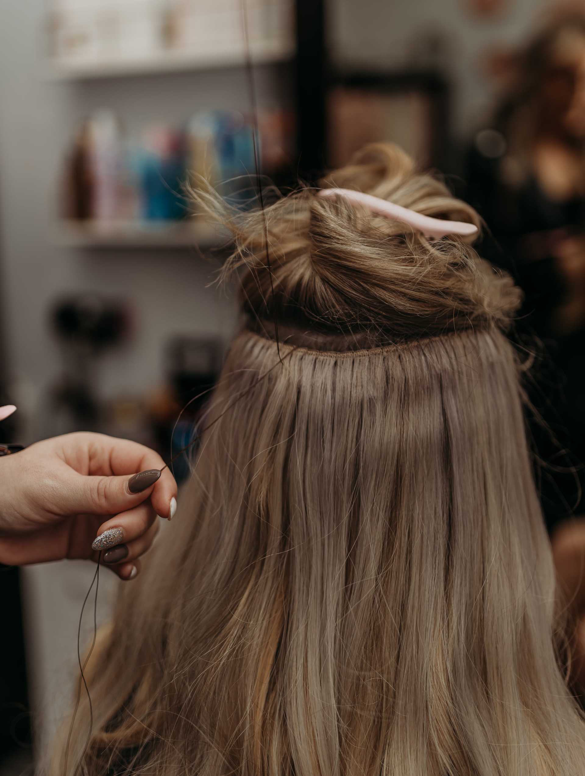 Hair extension being applied in a salon setting.